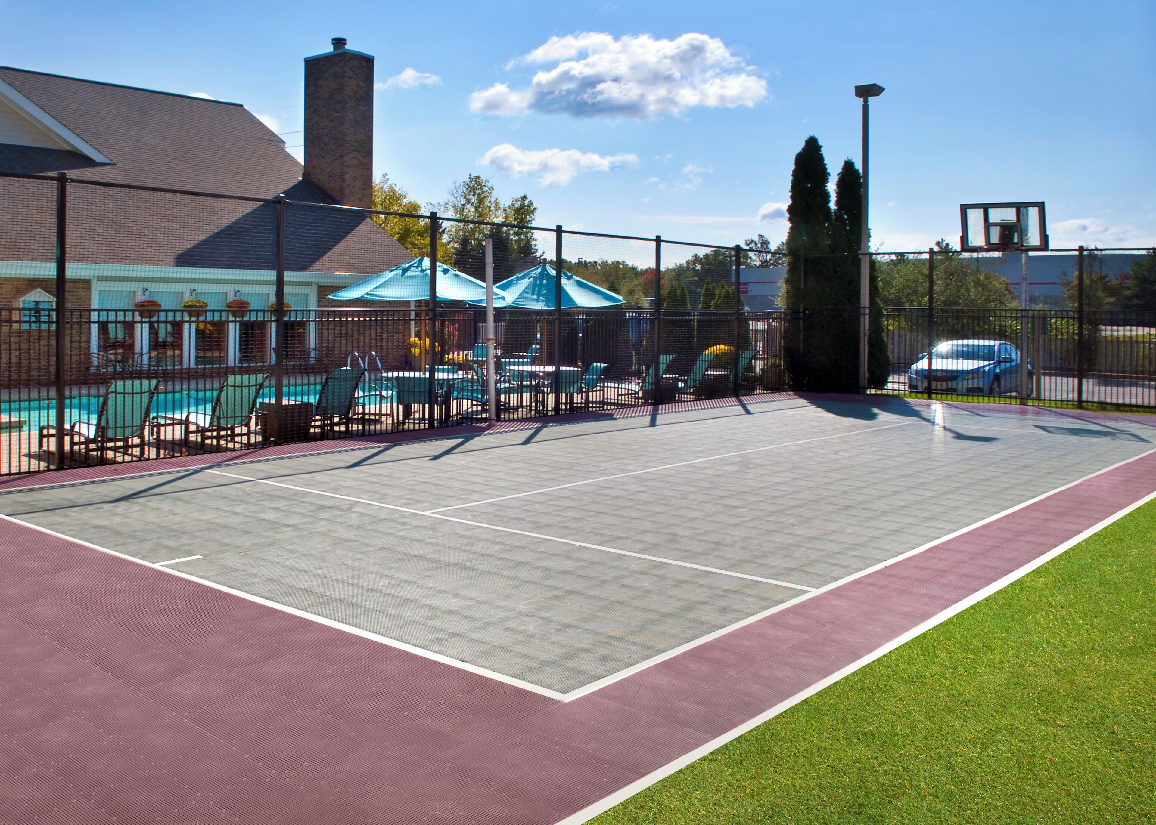 Ein Sportplatz im Freien mit Schwimmbad, Sitzbereich und einem eingezäunten Tennisplatz.