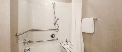 Ein Badezimmer mit einer Badewanne, einer Dusche, Haltegriffen und einem Handtuchhalter.