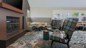 A modern lounge area with a fireplace, seating, and a patterned carpet. - Residence Inn by Marriott Boston North Shore/Danvers (Danvers)