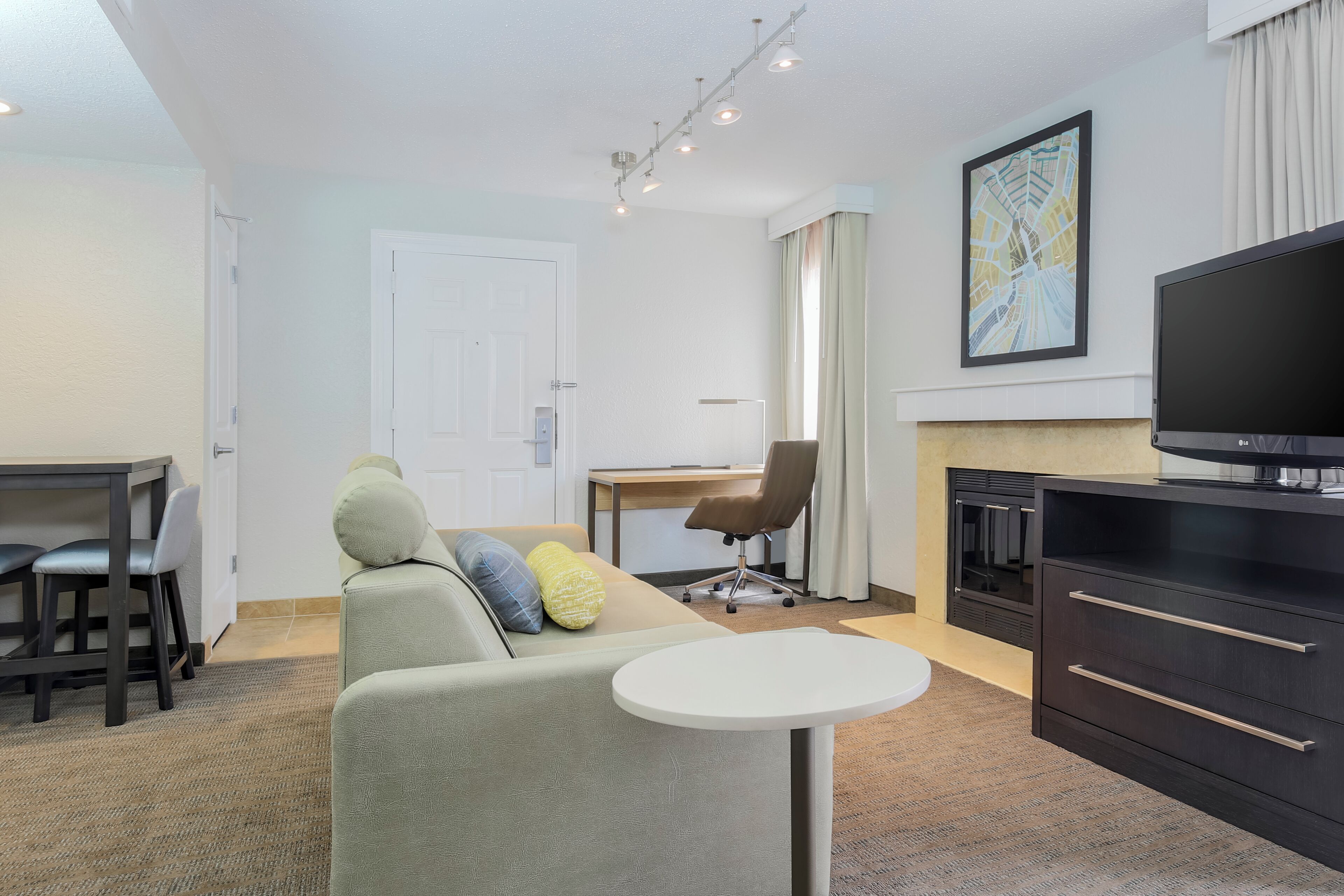A modern living room with a sofa, a dining table, a TV, and a fireplace.