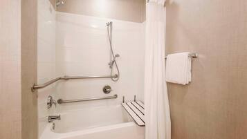 Un baño moderno con bañera, ducha, barras de apoyo y un perchero para toallas.