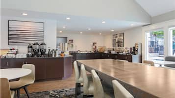 A modern kitchen with a large island, dark cabinetry, and a dining area with a long table and chairs.