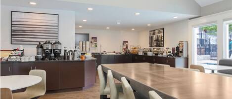 A modern kitchen with a large island, dark cabinetry, and a dining area with a long table and chairs.