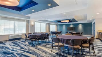 A conference room with round tables and chairs, large windows, and a blue accent wall.