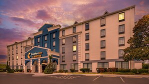 A hotel with a prominent sign for Comfort Inn & Suites, featuring a modern design with multiple floors and a parking lot in front.