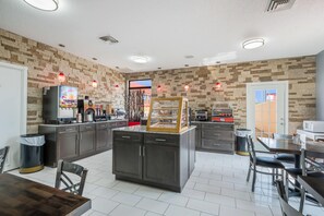 A modern kitchen with granite countertops, a central island, and a dining area with a table and chairs.