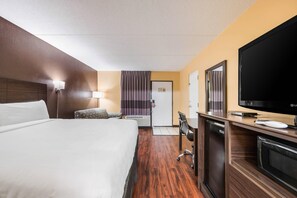 A hotel room with a bed, a desk with a television, a chair, and a window with curtains. - Econo Lodge Columbus near Airport (Columbus)