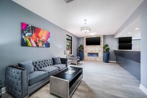 A modern living room with a grey sofa, a coffee table, and a fireplace.
