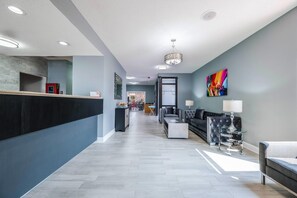 A modern hotel lobby with a reception desk, seating area, and a colorful abstract painting. - Econo Lodge Columbus near Airport (Columbus)