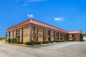 A motel with a red roof, multiple balconies, and a parking lot. - Econo Lodge Columbus near Airport (Columbus)