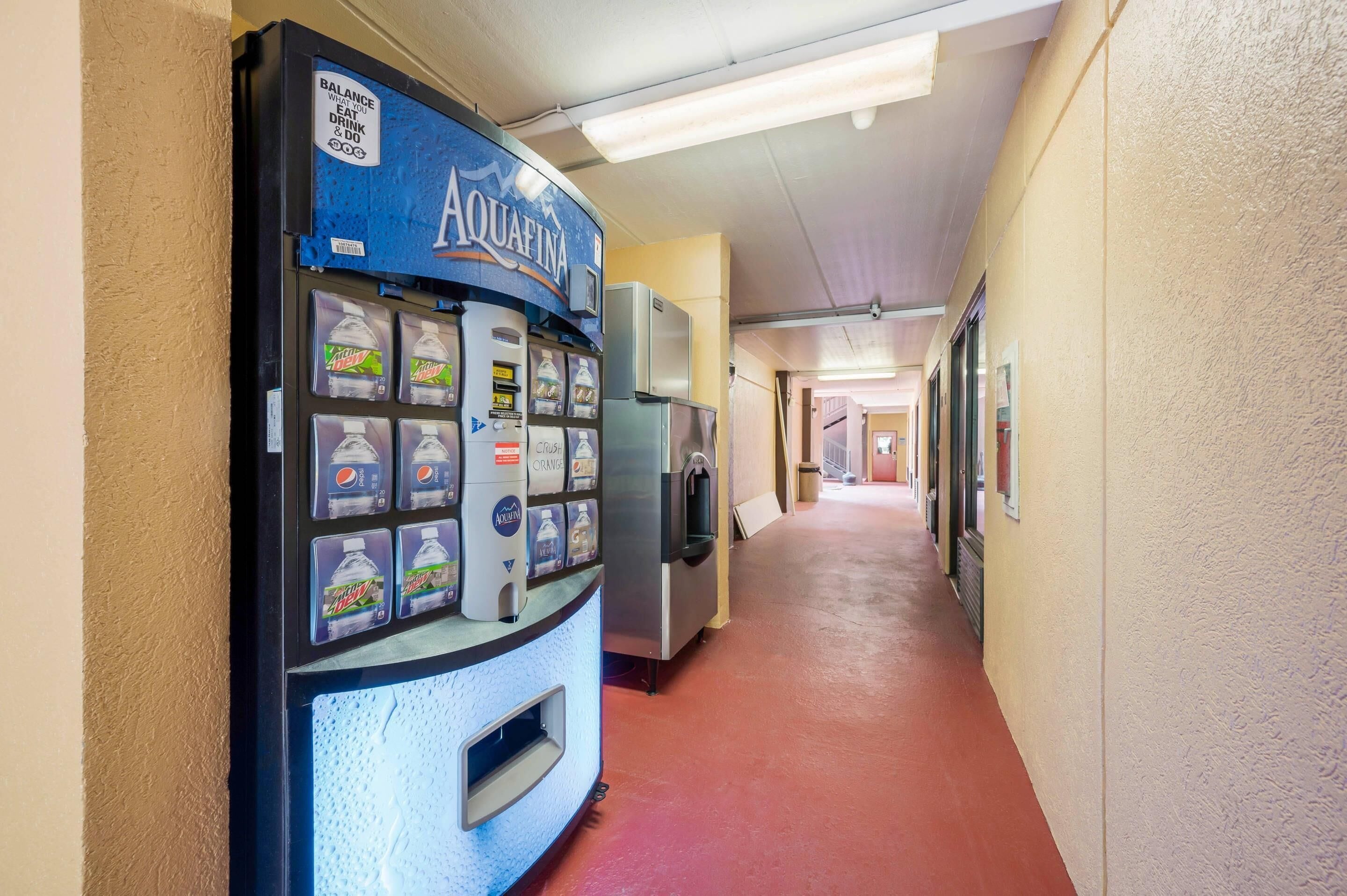 A hallway with a water vending machine on the left and a refrigerator on the right.