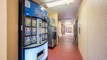 A hallway with a water vending machine on the left and a refrigerator on the right.