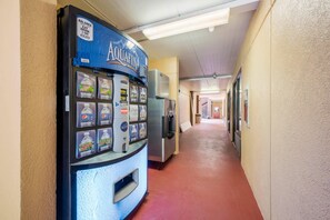 A hallway with a water vending machine on the left and a refrigerator on the right. - Econo Lodge Columbus near Airport (Columbus)