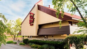Un hotel Red Roof Inn con un llamativo letrero rojo y negro, un techo inclinado y un revestimiento de piedra.