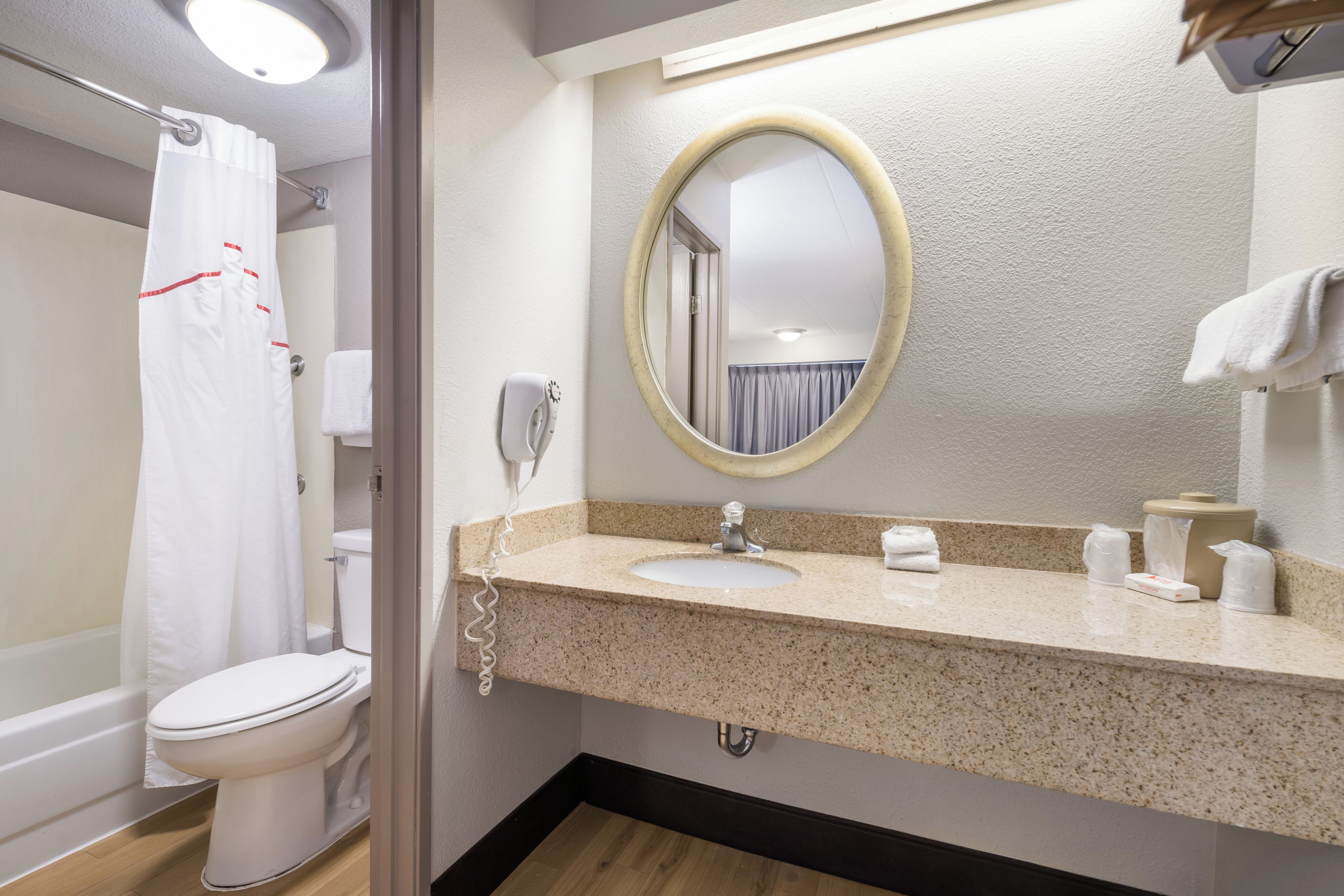 A bathroom with a toilet, sink, mirror, and shower curtain.