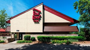 A Red Roof Inn with a red roof, beige walls, and a stone foundation. - Red Roof Inn Rockford East – Casino District (Rockford)