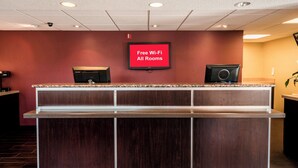 Un mostrador de recepción con un televisor de pantalla plana mostrando 'Wi-Fi gratuito en todas las habitaciones' en un vestíbulo de hotel.
