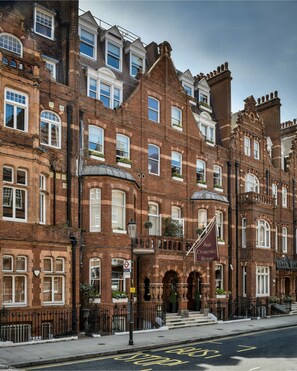 A row of red brick Victorian-style buildings with multiple windows and a prominent entrance with a flag. - San Domenico House (London)