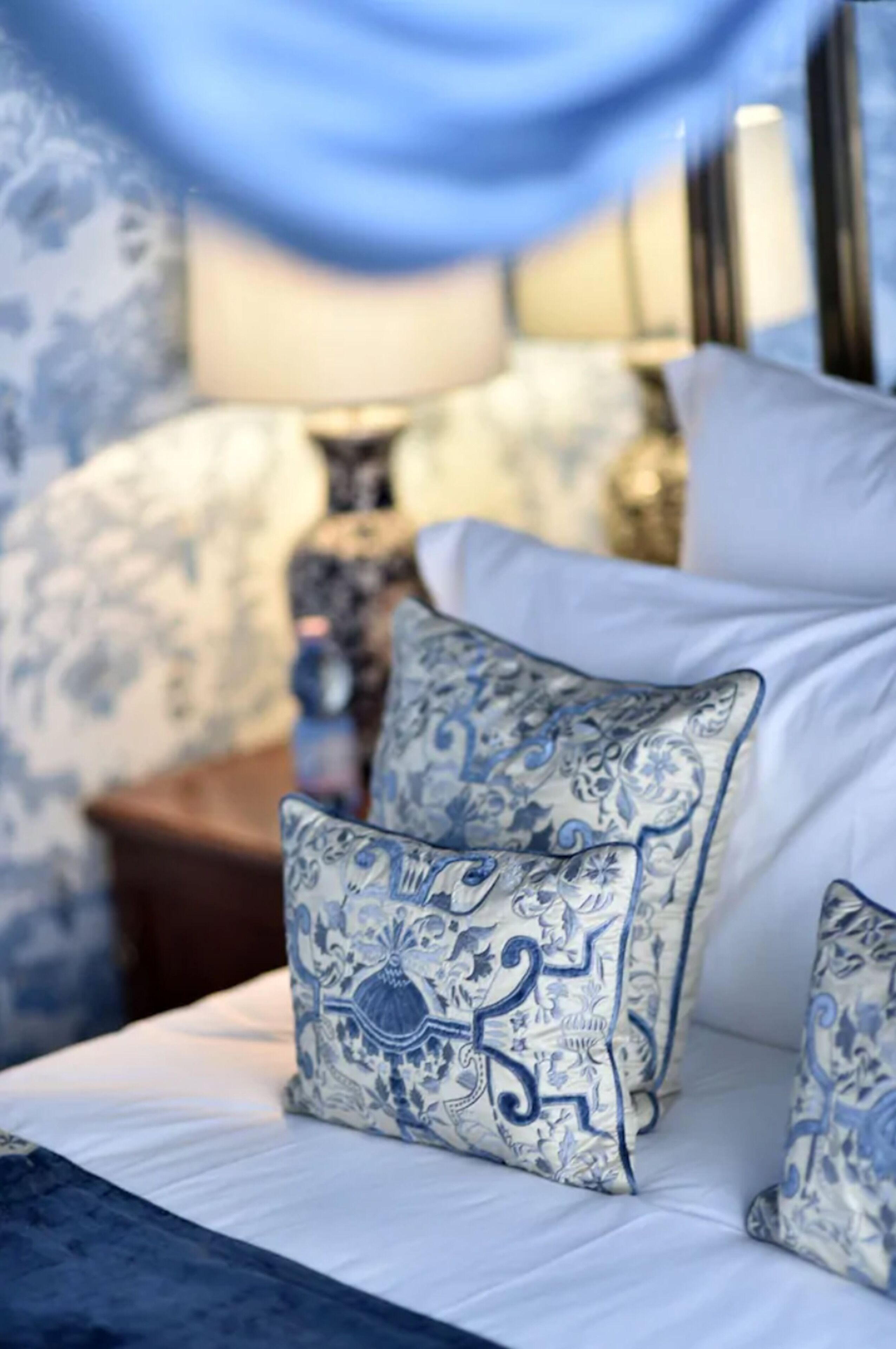 Ein Bett mit weißer Bettwäsche und blauen Kissen mit Muster.