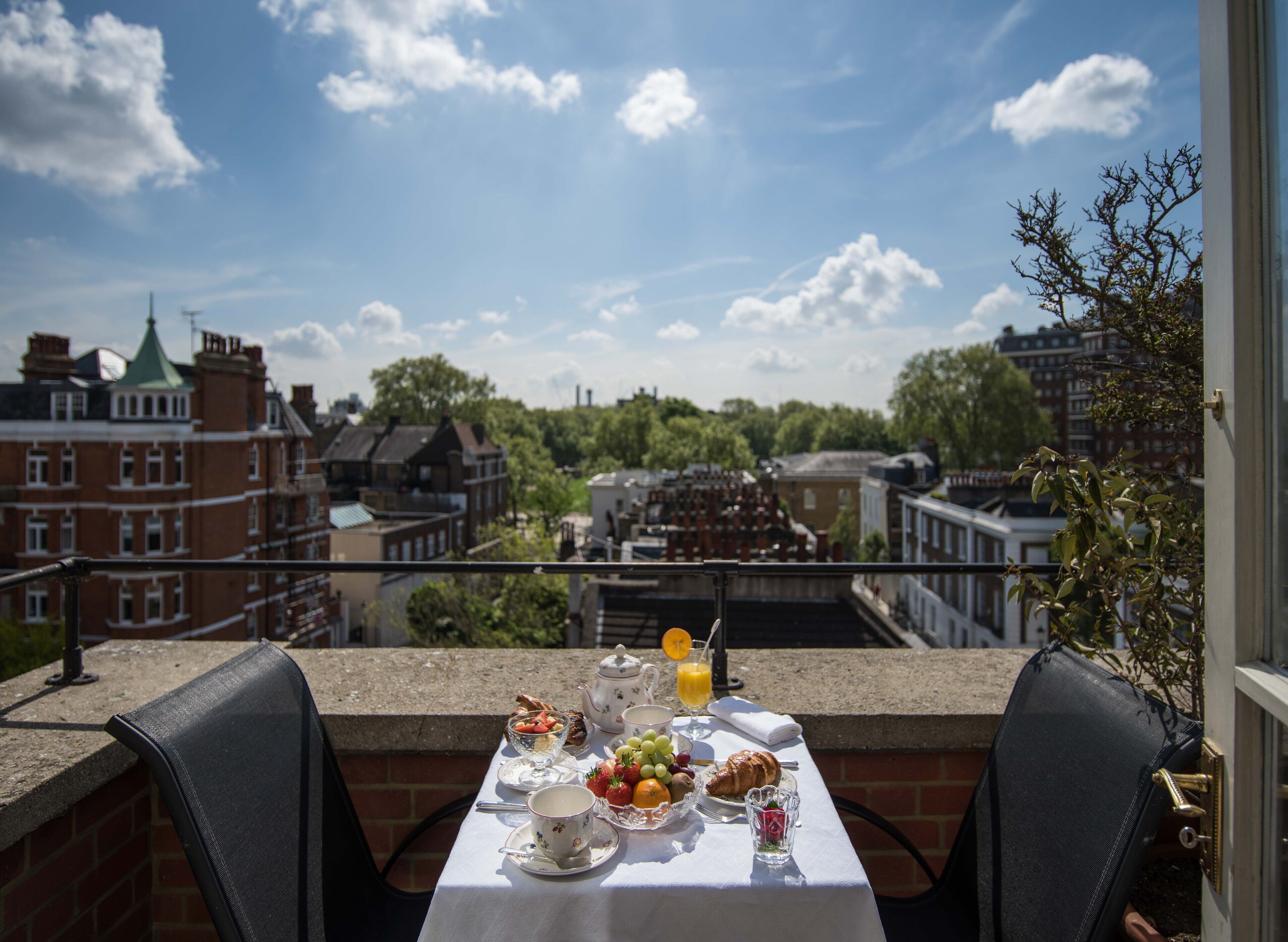 A table set with breakfast items on a balcony overlooking a cityscape.