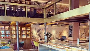 A modern interior with a central counter displaying pastries, surrounded by seating and a patterned floor. - Hotel Duca D'Aosta (Aosta)