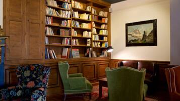 Une bibliothèque avec des étagères en bois, un tableau au mur et des fauteuils à revêtement vert.