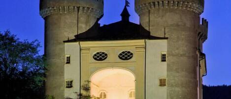 A castle-like structure with two prominent towers, a central arched entrance, and a balcony with railings.