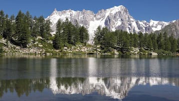 A mountain lake with reflections, surrounded by evergreen trees and rocky terrain.