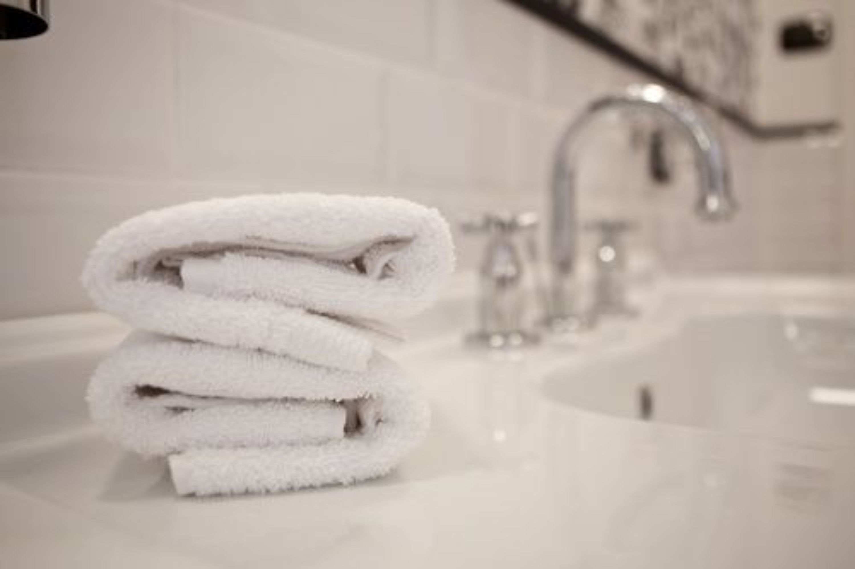 A stack of white towels on a bathroom sink.