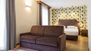 Une chambre avec un canapé marron, un lit doté d’une tête de lit en bois, une table de chevet et un mur orné d’un motif.