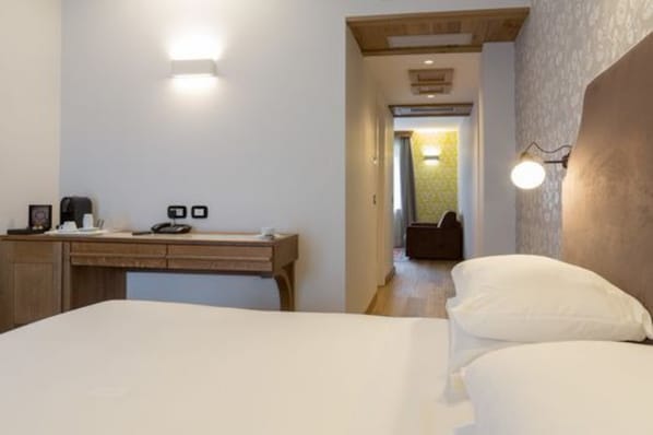 A hotel room with a bed, a desk with a telephone and a coffee maker, and a wall-mounted light fixture. - Hotel Duca D'Aosta (Aosta)