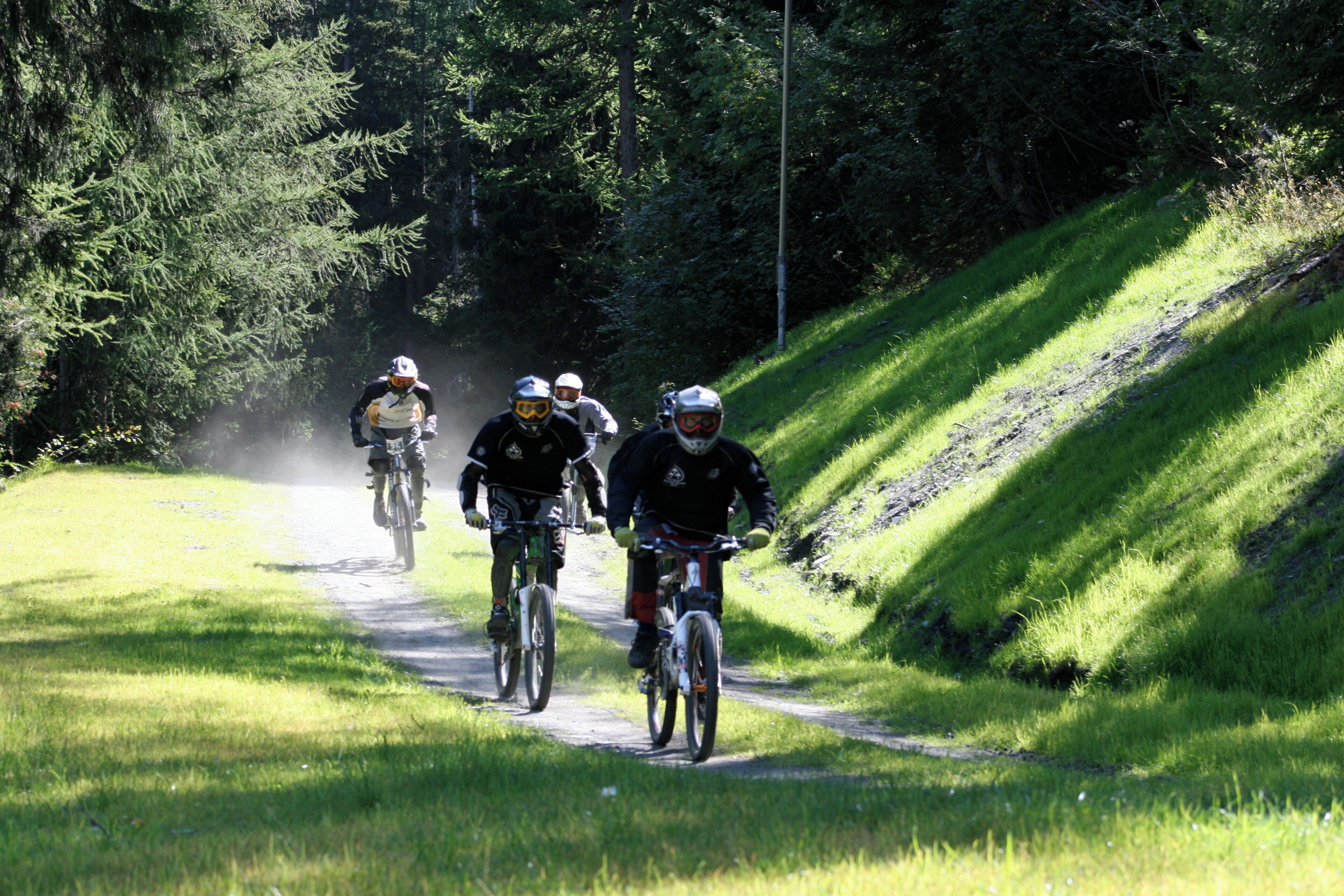 A group of cyclists on a dirt path surrounded by greenery.