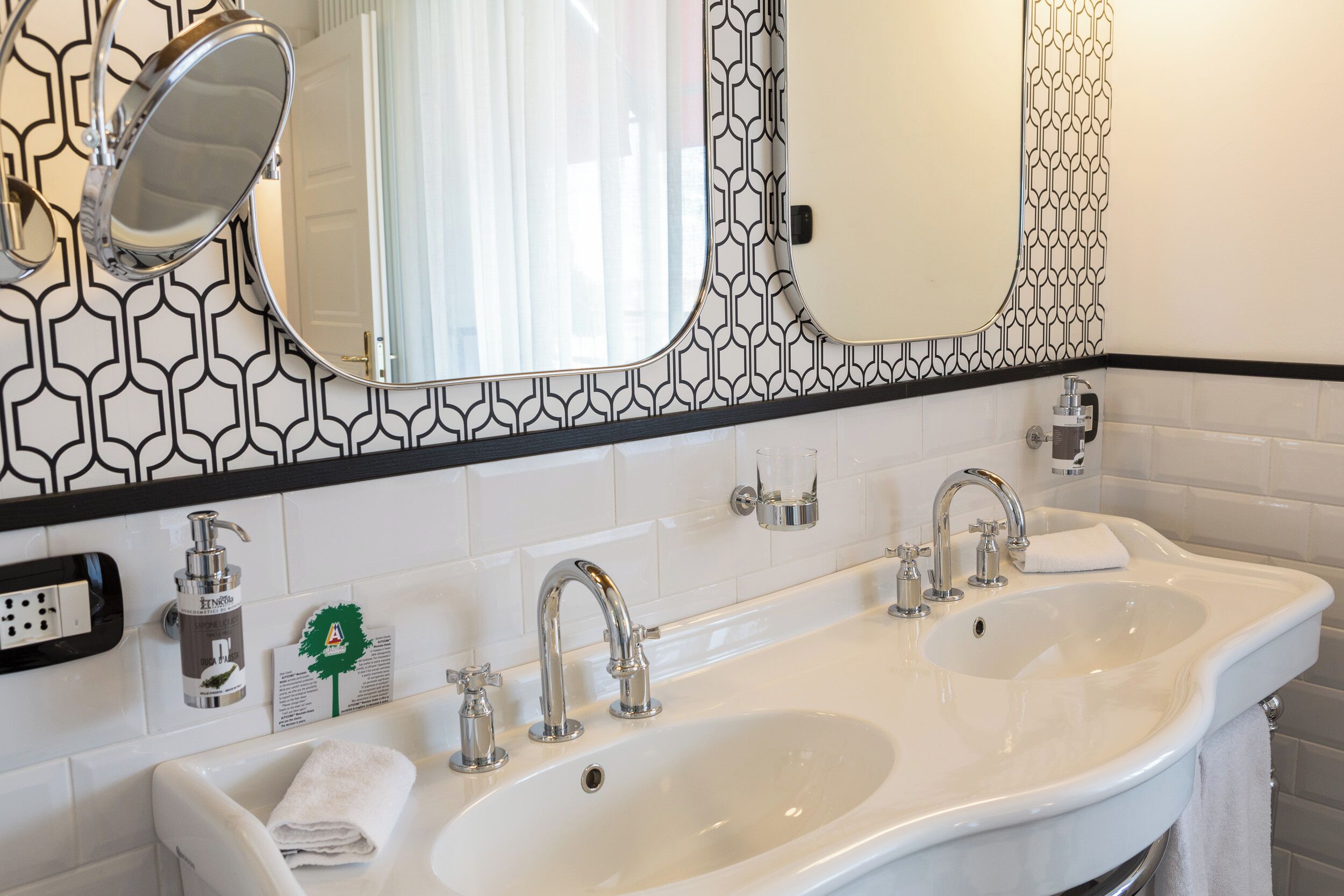 A bathroom with two sinks, a mirror, and a patterned wall.