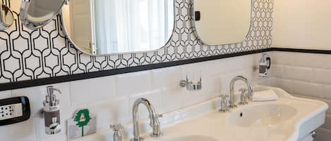 A bathroom with two sinks, a mirror, and a patterned wall.