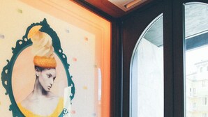 A bakery interior with a large window, a door with a glass panel, and a wall with a framed illustration. - Hotel Duca D'Aosta (Aosta)