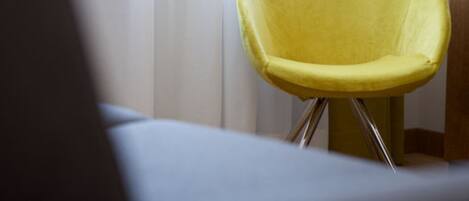 A yellow chair with a metal frame in a room with a window and curtains.