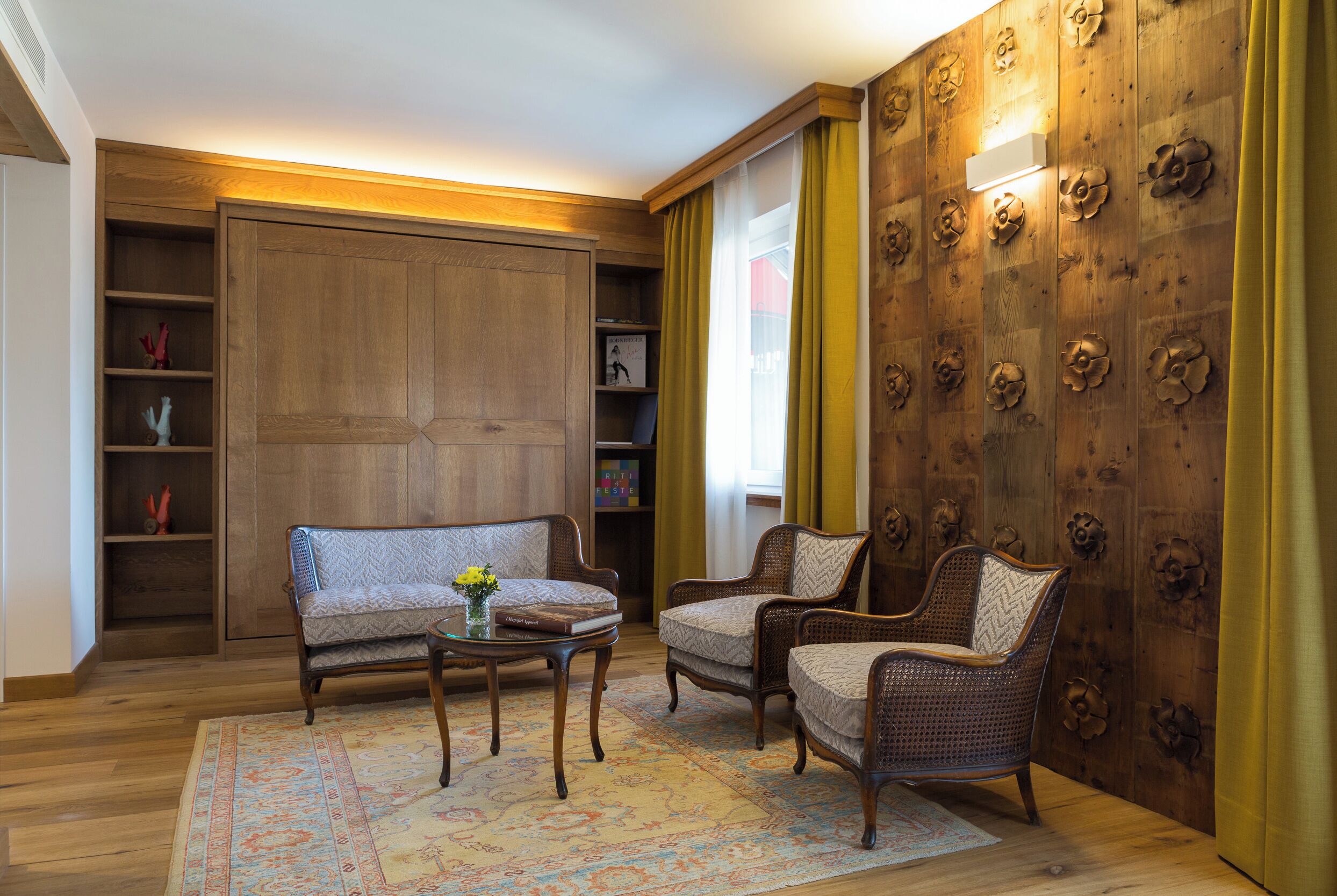 A room with a sofa, two armchairs, a small table, and a patterned rug.