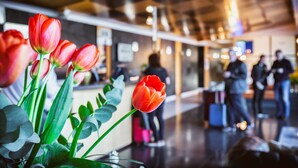 Een hotel lobby met een receptiebalie, een incheckruimte en een groep mensen op de achtergrond.