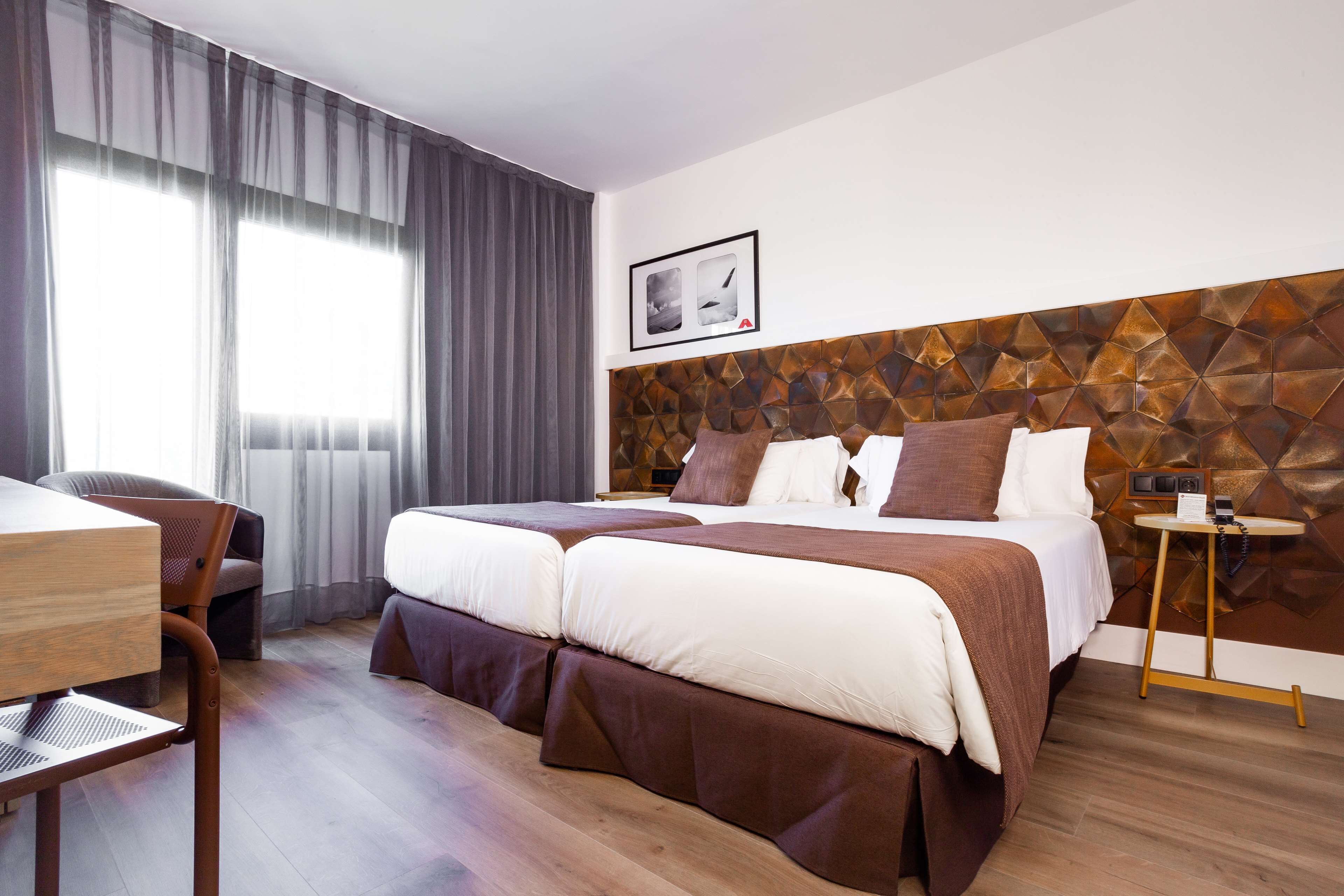 A hotel room with a large bed, a desk, and a chair.
