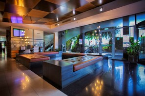 Eine moderne Lobby mit einer zentralen Sitzecke, einer Treppe und Blick ins Freie.
