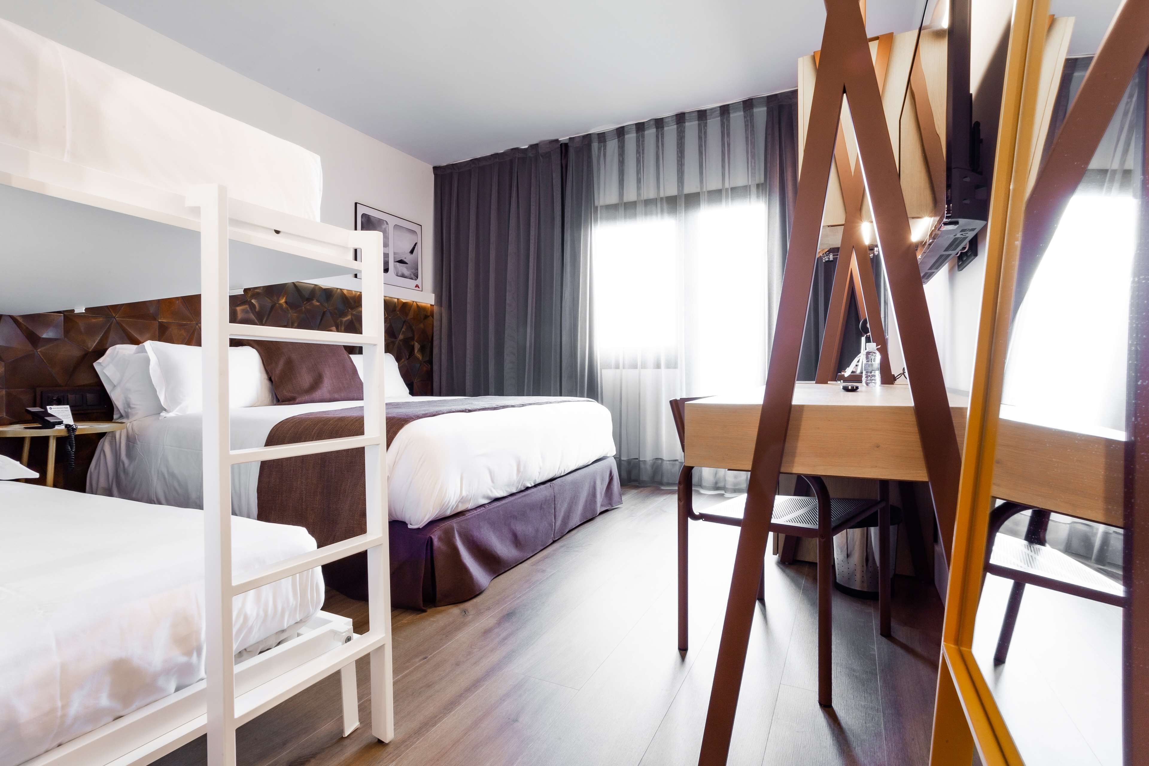 Een hotelkamer met stapelbedden, een bureau en een stoel.