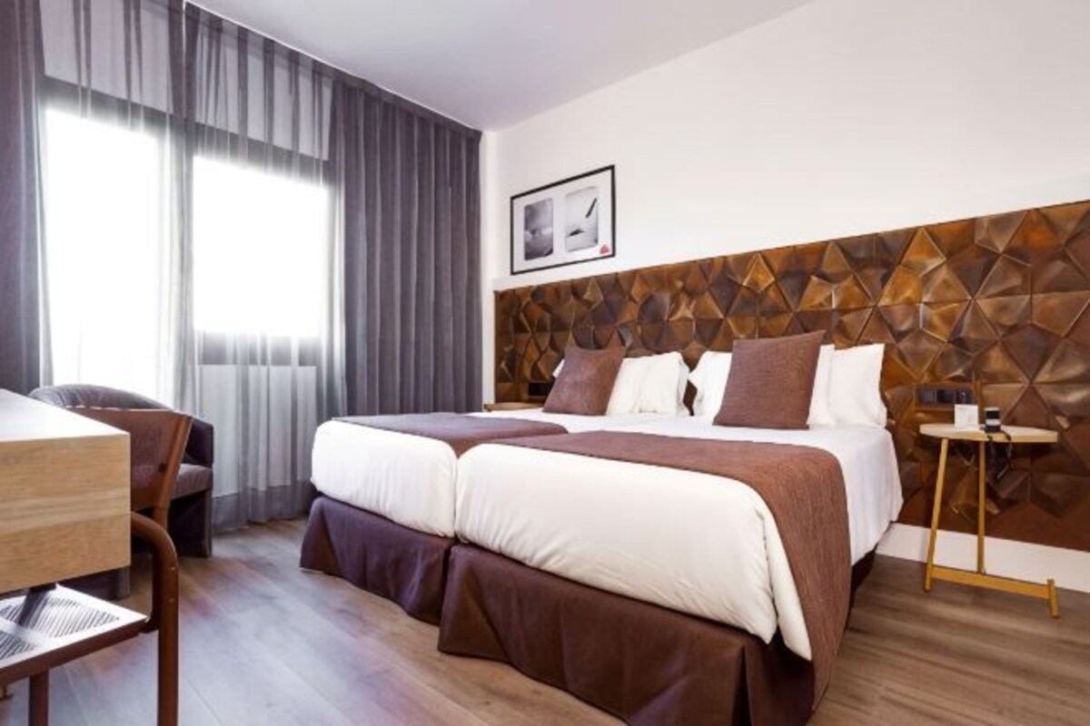 A hotel room with a double bed, a desk, and a chair.