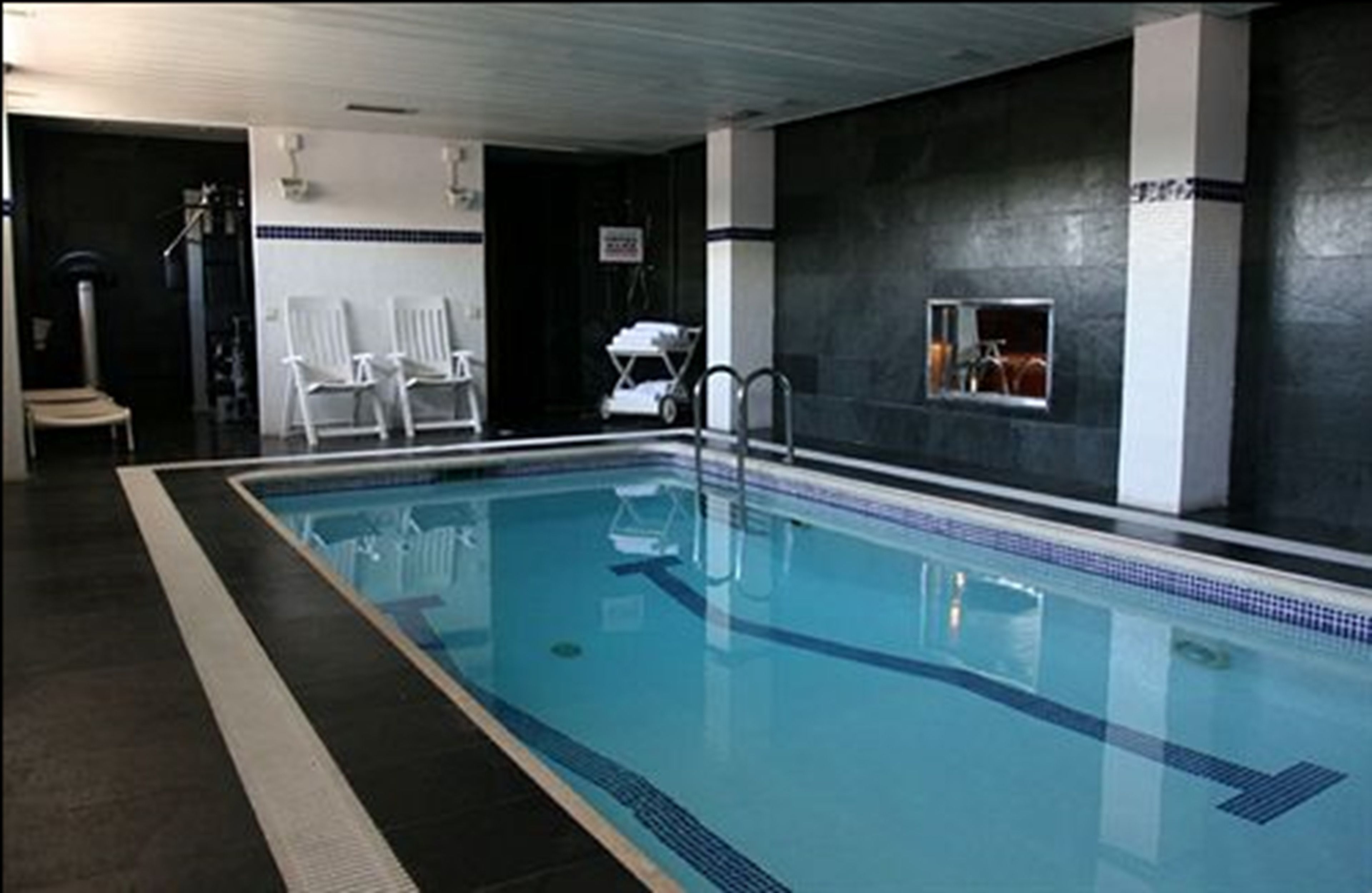 A swimming pool with clear water, surrounded by dark walls and white pillars.
