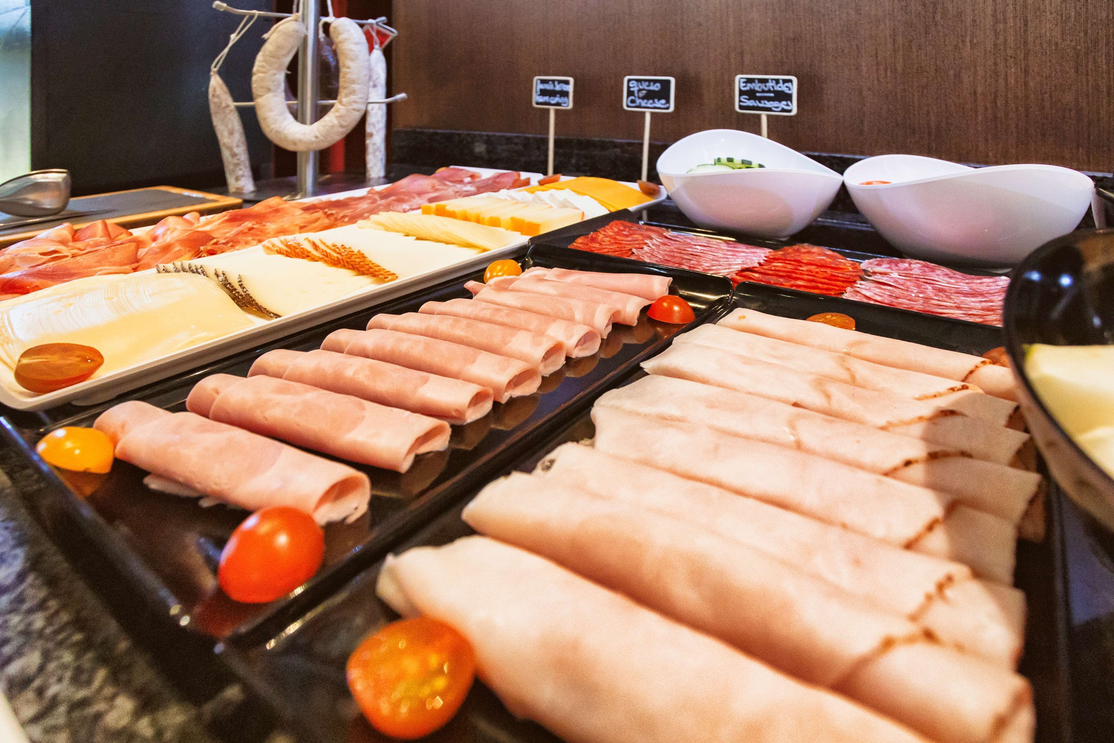 A buffet with various meats and cheeses.