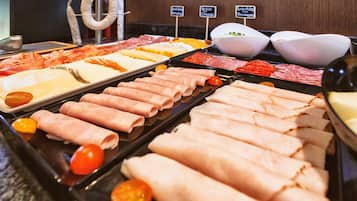 A buffet with various meats and cheeses.
