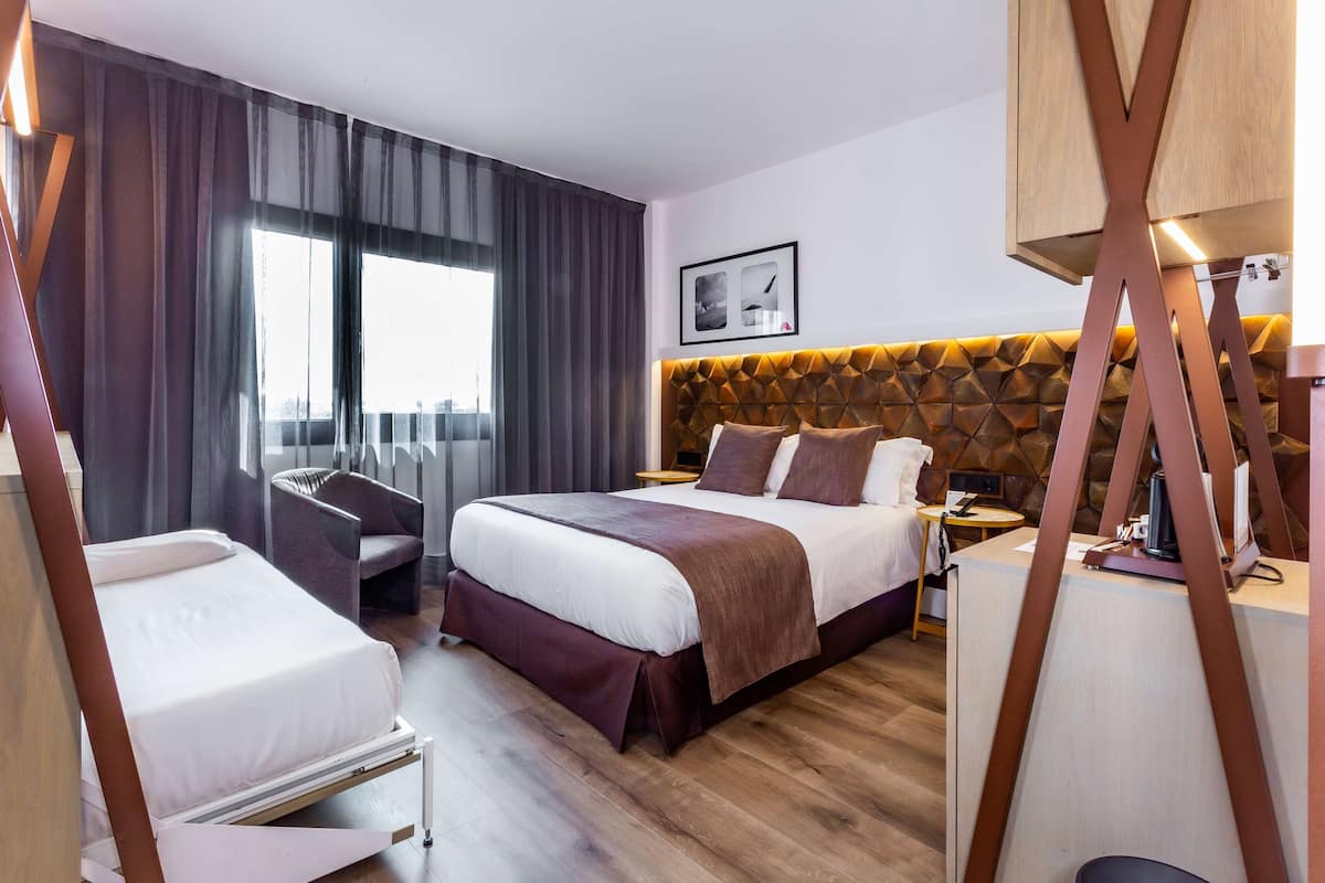Ein modernes Hotelzimmer mit einem großen Bett, einem Schreibtisch und einem Stuhl.