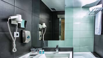 A modern bathroom with a white sink, a mirror, a hairdryer, and a towel rack.