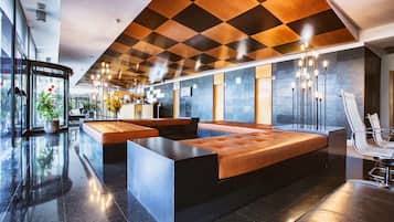 A modern lobby with a checkered ceiling, a reception desk, seating areas, and a large, cushioned reception desk.