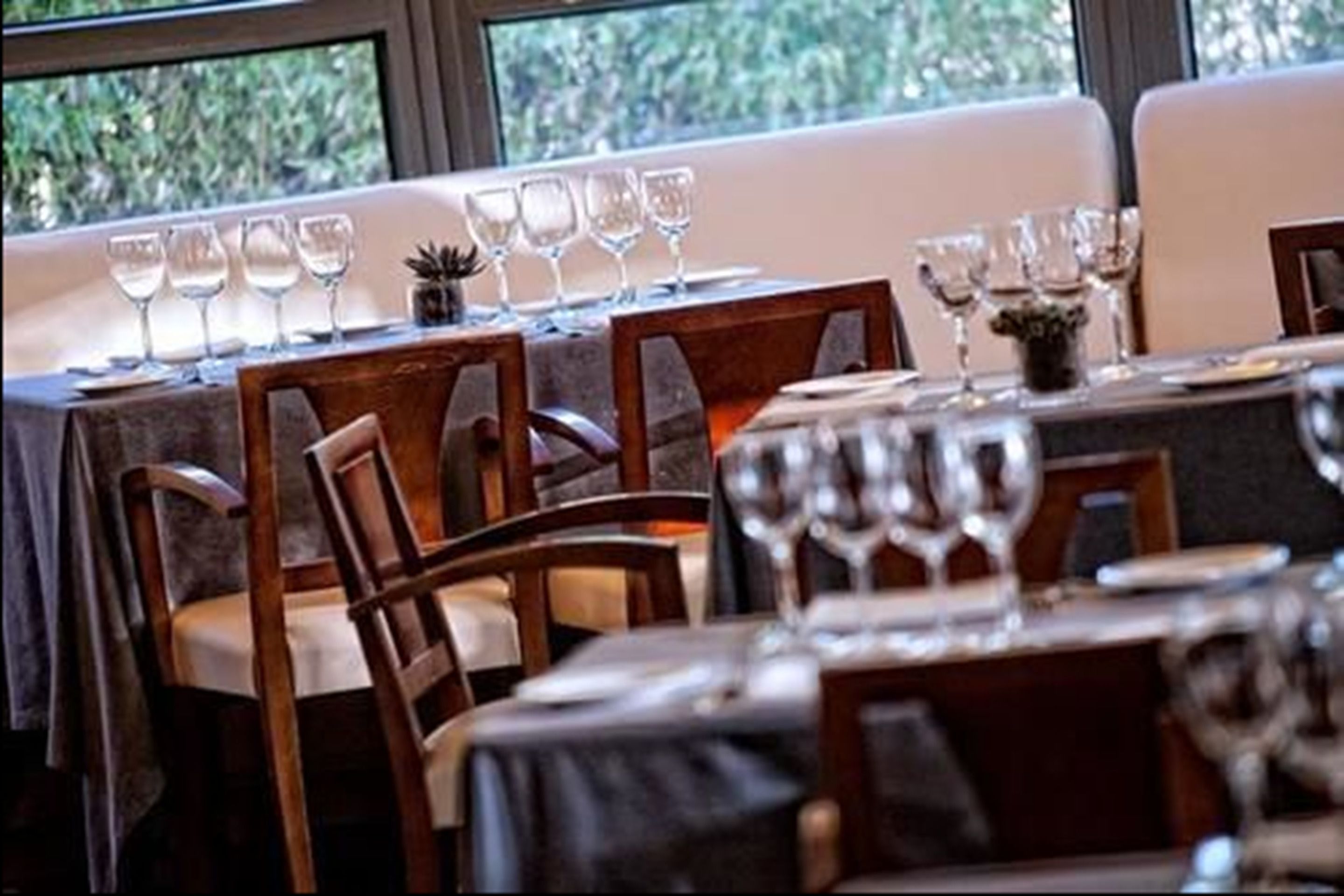 Een restaurant met gedekte tafels, stoelen en wijnglazen.