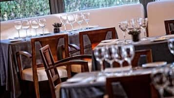 Un restaurante con mesas dispuestas para comer, sillas y copas de vino.